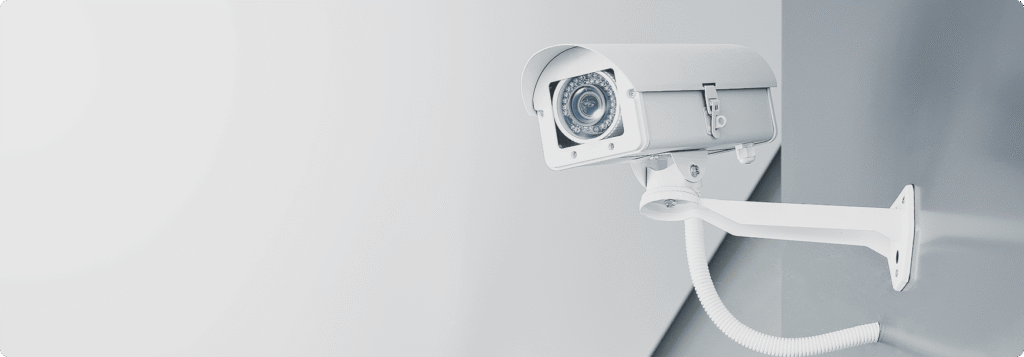 Caméra de vidéosurveillance blanche fixée au mur illustrant la sûreté des locaux professionnels